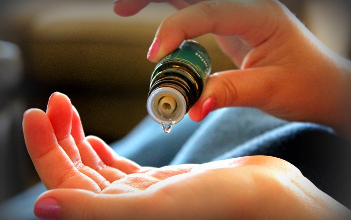 close-up of using essential oil on skin