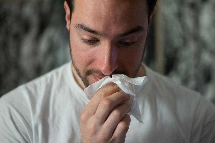 picture of a men holding a tissue to his nose