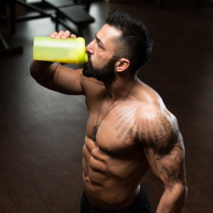 man drinking water from a yellow protein shaker